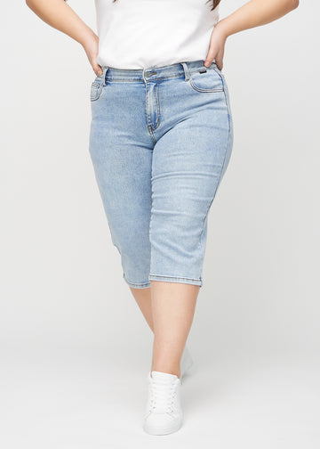 Hellblaue Denim-regular-Capris, Modellname Waves, die gerade am Bein sitzen und direkt unter dem Knie enden, an einem Plus-Size-Model von vorn gesehen.