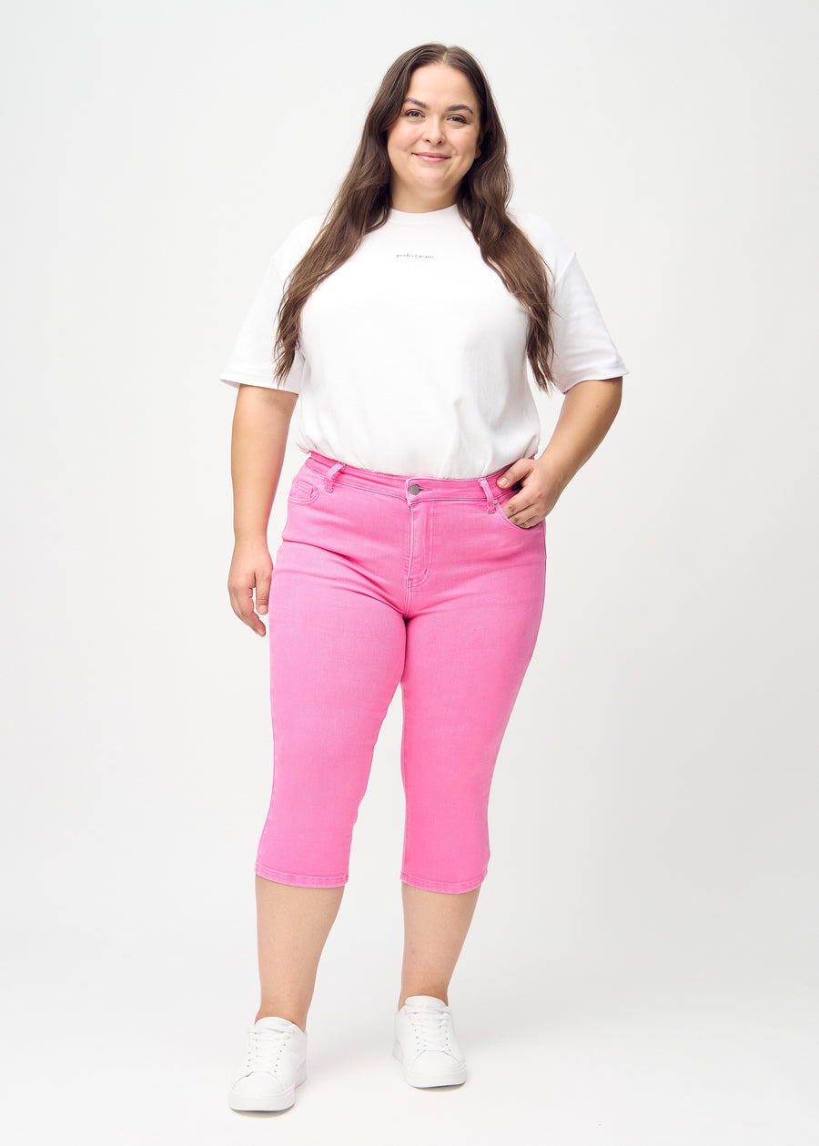 Skinny-Capris für Damen in pastellrosa Jeansstoff, Farbe Flamingos. Ganzkörperansicht eines Plus-Size-Models in den Capris.