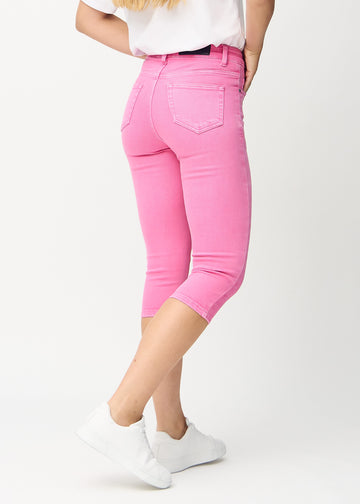 Skinny-Capris für Damen in pastellrosa Jeansstoff, Farbe Flamingos. Rückansicht an einem Model, zeigt die Passform und Gesäßtaschen.