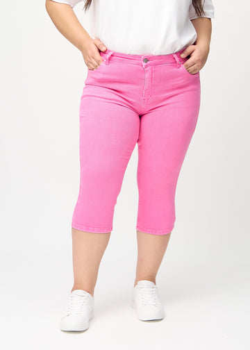 Skinny-Capris für Damen in pastellrosa Jeansstoff, Farbe Flamingos. Vorderansicht an einem Plus-Size-Model, eng geschnitten bis knapp unter das Knie.