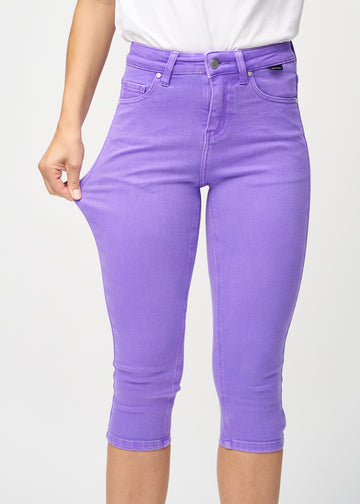 Skinny-Capris für Damen in pastellviolettem Jeansstoff, Farbe Lavenders. Ein Model dehnt den Stoff, um den Stretch zu zeigen.