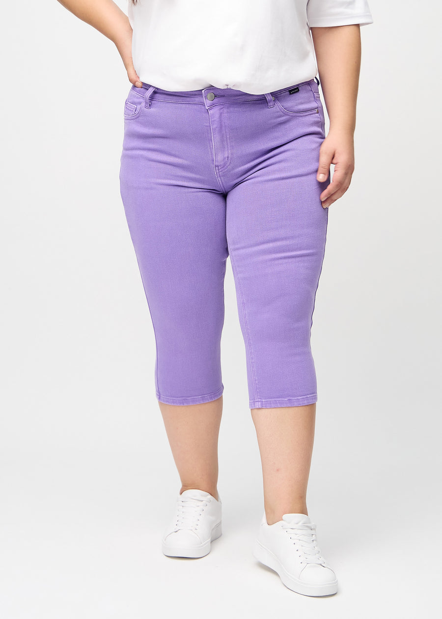 Skinny-Capris für Damen in pastellviolettem Jeansstoff, Farbe Lavenders. Vorderansicht an einem Plus-Size-Model, eng geschnitten bis knapp unter das Knie.