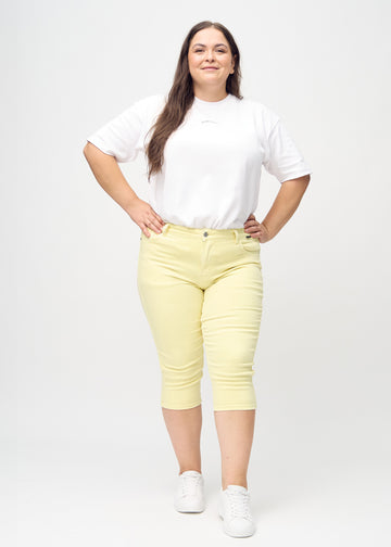 Ganzkörperbild eines Plus-Size-Models in hellgelben skinny Capris.