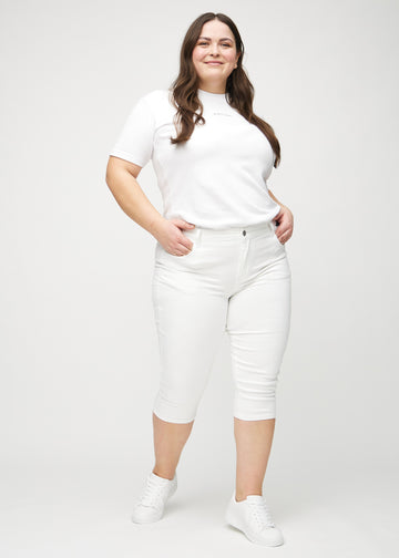 Ganzkörperbild eines Plus-Size-Models in weißen skinny Capris.