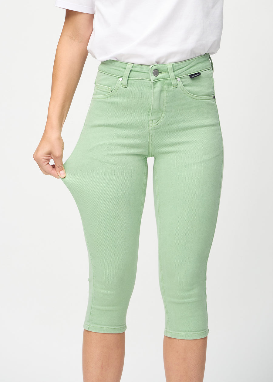 Skinny-Capris für Damen in pastellgrünem Jeansstoff, Farbe Mints. Ein Model dehnt den Stoff, um den Stretch zu zeigen.