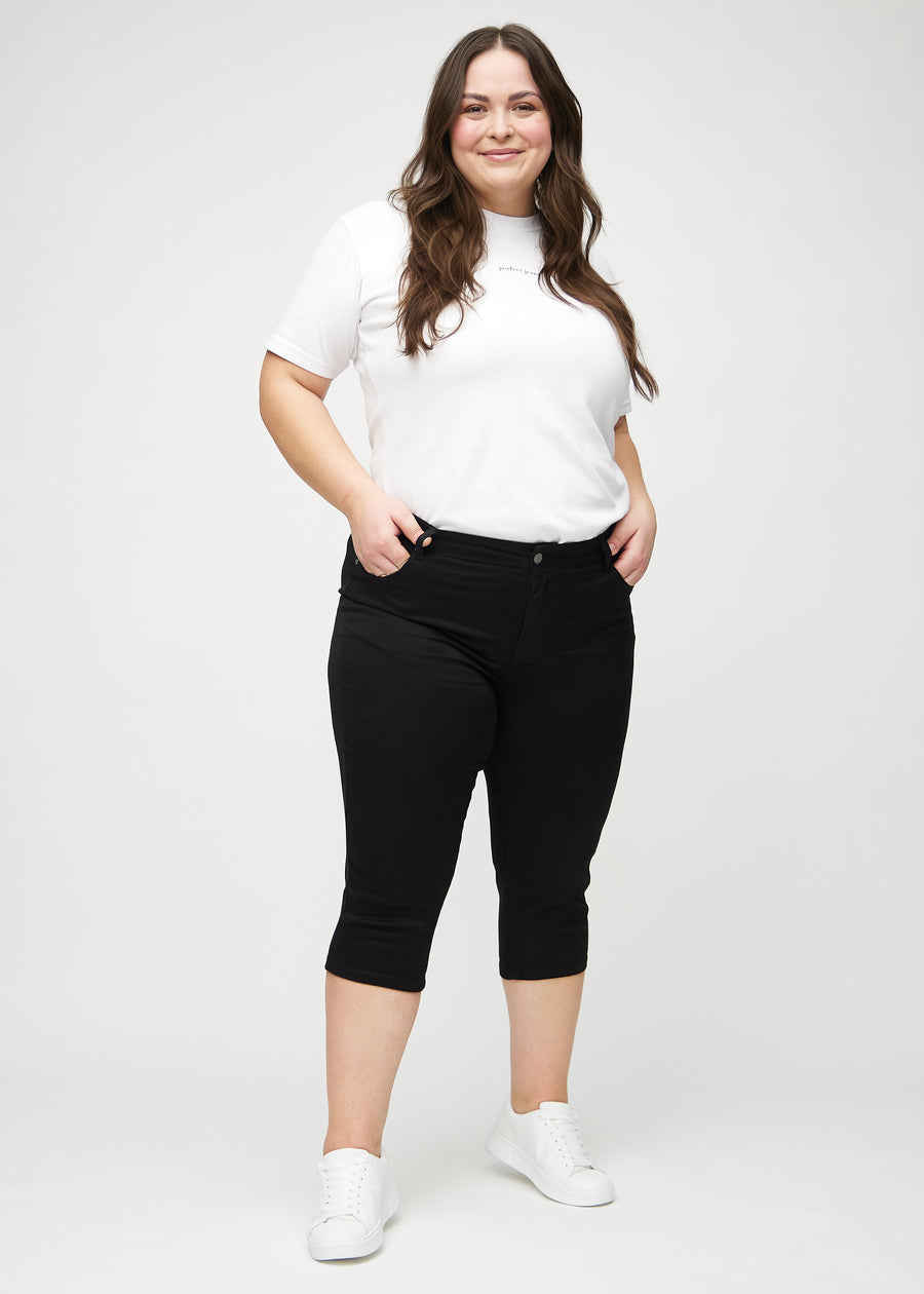 Ganzkörperbild eines Plus-Size-Models in schwarzen skinny Capris.