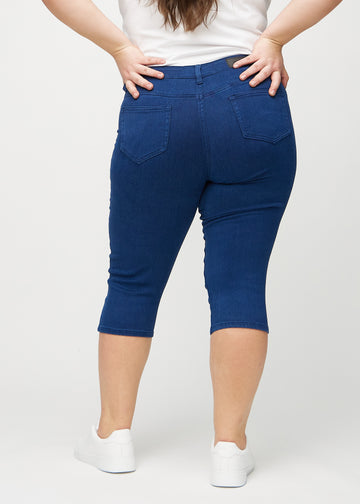 Skinny-Capris für Damen in dunkelblauem Jeansstoff, Farbe Royals. Rückansicht an einem Plus-Size-Model, zeigt die Passform und Gesäßtaschen.