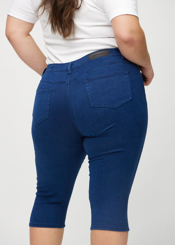 Skinny-Capris für Damen in dunkelblauem Jeansstoff, Farbe Royals. Nahaufnahme von hinten an einem Plus-Size-Model, zeigt Taschen und Nähte.