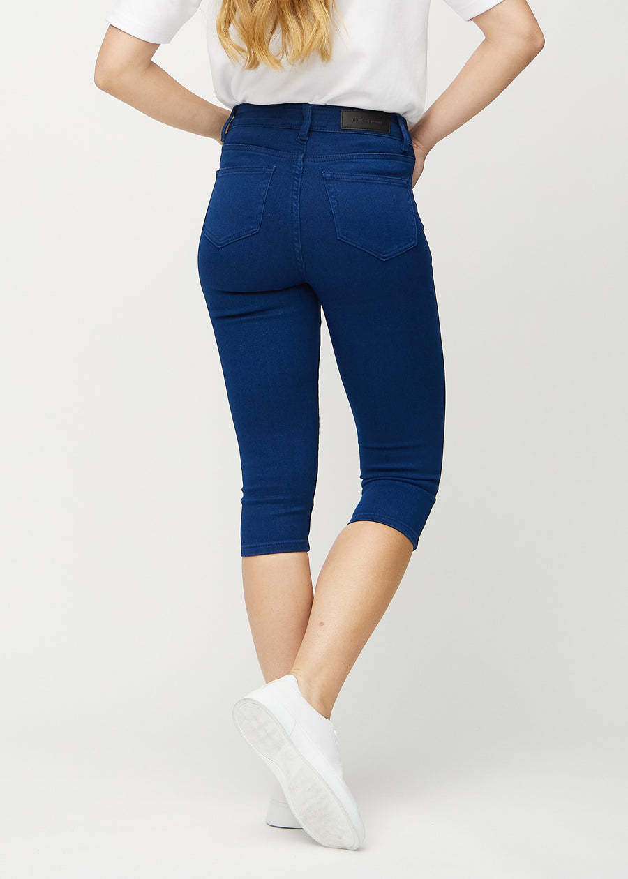 Skinny-Capris für Damen in dunkelblauem Jeansstoff, Farbe Royals. Rückansicht an einem Model, zeigt die Passform und Gesäßtaschen.