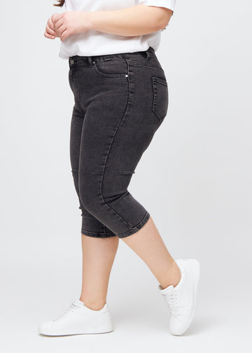Skinny-Capris für Damen in dunkelgrauem Denim, Farbe Shadows. Seitenansicht an einem Plus-Size-Model, die figurbetonte Passform ist zu sehen.
