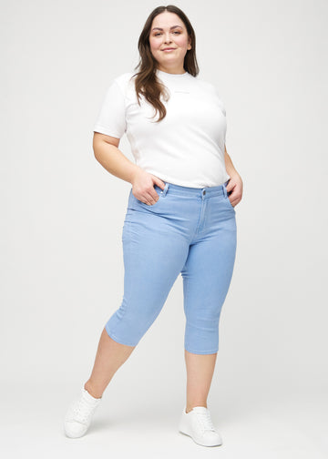 Skinny-Capris für Damen in hellblauem Jeansstoff, Farbe Skies. Ganzkörperansicht eines Plus-Size-Models in den Capris.