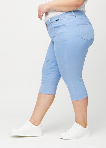 Skinny-Capris für Damen in hellblauem Jeansstoff, Farbe Skies. Seitenansicht an einem Plus-Size-Model, die figurbetonte Passform ist zu sehen.