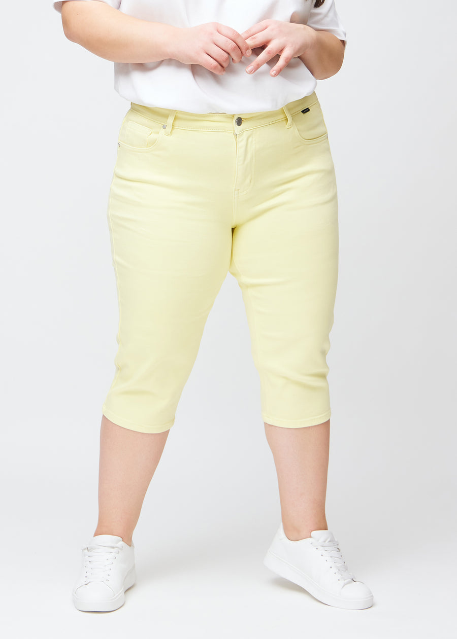 Hellgelbe slim Capris, Farbe Lemonades, mit eng anliegender Passform und Länge direkt unter dem Knie, von vorne an einem Plus-Size-Model gesehen.
