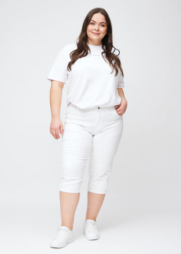 Slim-Capris für Damen aus weißem Jeansstoff, Farbe Marguerites. Ganzkörperansicht eines Plus-Size-Models in den Slim-Capris.