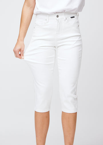 Slim-Capris für Damen aus weißem Jeansstoff, Farbe Marguerites. Ein Model dehnt den Stoff am Oberschenkel, um die Flexibilität zu zeigen.