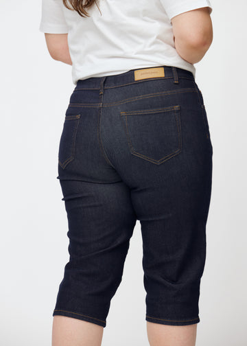 Tief dunkelblaue Denim-Capris für Damen in der Farbe Midnights von hinten nah auf einem Plus-Size-Model aufgenommen.