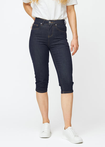 Tief dunkelblaue Denim-Capris für Damen in der Farbe Midnights mit Slim-Passform, die von der Hüfte bis unter das Knie figurbetont geschnitten ist, von vorne gesehen.