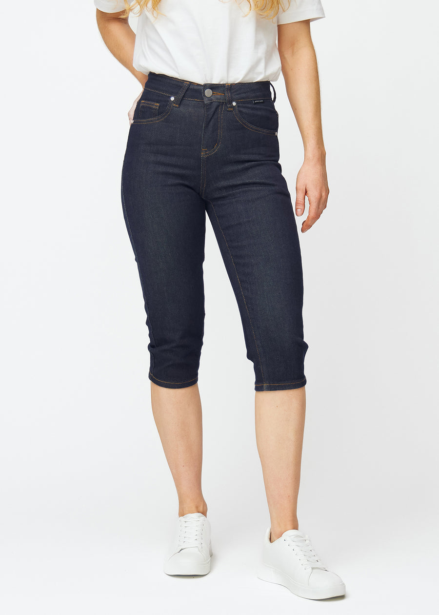 Tief dunkelblaue Denim-Capris für Damen in der Farbe Midnights mit Slim-Passform, die von der Hüfte bis unter das Knie figurbetont geschnitten ist, von vorne gesehen.