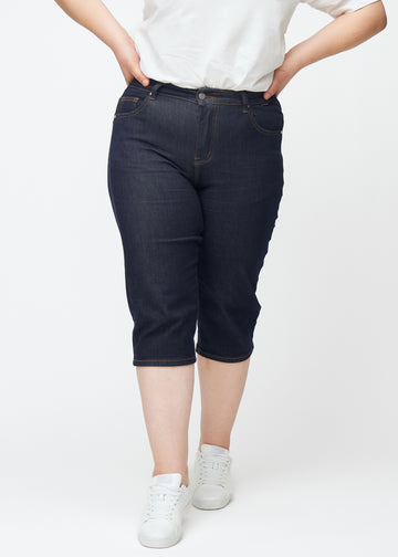 Tief dunkelblaue Denim-Capris für Damen in der Farbe Midnights mit Slim-Passform, von vorne auf einem Plus-Size-Model gesehen.