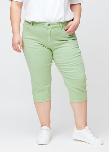 Slim-Capris für Damen aus pastellhellgrünem Jeansstoff, Farbe Mints. Vorderansicht an einem Plus-Size-Model, figurbetonter Schnitt bis knapp unter das Knie.