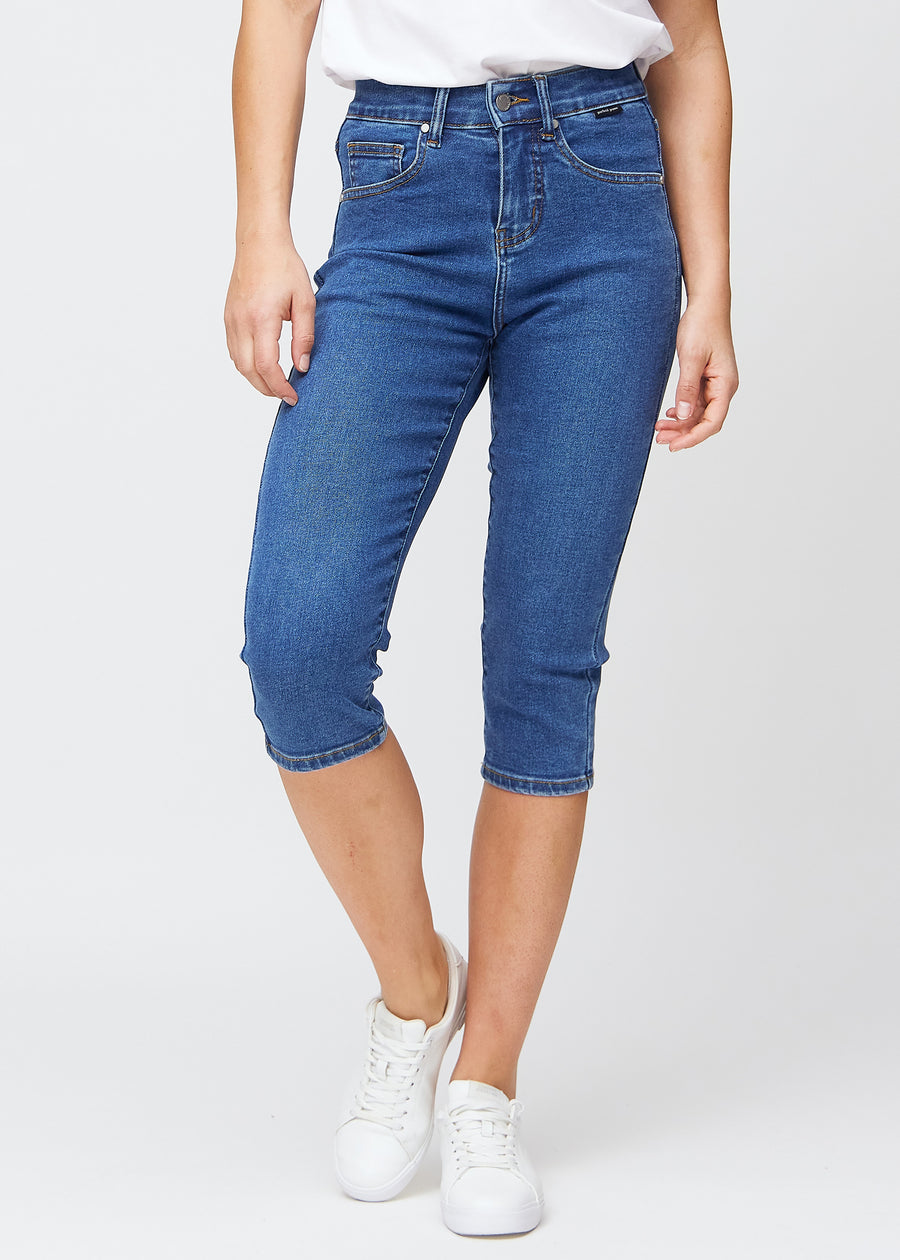 Slim-Capris für Damen aus dunkelblauem Denim, Farbe Oceans. Vorderansicht an einem Model, figurbetonter Schnitt bis knapp unter das Knie.