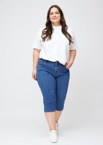 Slim-Capris für Damen aus dunkelblauem Denim, Farbe Oceans. Ganzkörperansicht eines Plus-Size-Models in den Slim-Capris.
