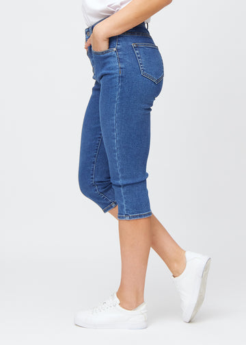 Slim-Capris für Damen aus dunkelblauem Denim, Farbe Oceans. Seitenansicht an einem Model, figurbetonter Schnitt und mittelhoher Bund (Mid Rise).