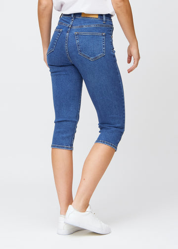 Slim-Capris für Damen aus dunkelblauem Denim, Farbe Oceans. Rückansicht an einem Model, zeigt Passform, Länge und Gesäßtaschen.