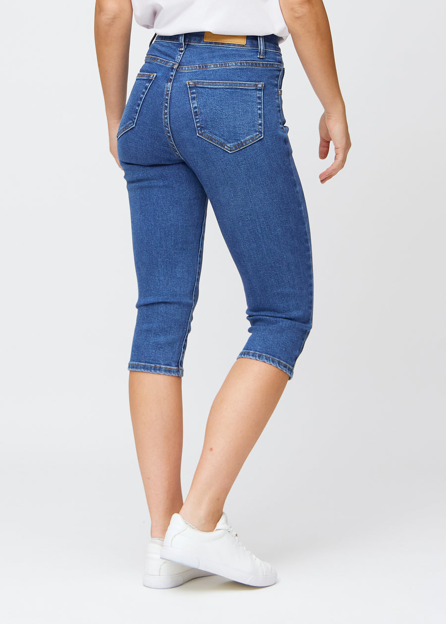 Slim-Capris für Damen aus dunkelblauem Denim, Farbe Oceans. Rückansicht an einem Model, zeigt Passform, Länge und Gesäßtaschen.
