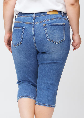 Slim-Capris für Damen aus blauem Denim, Farbe Rivers. Nahaufnahme von hinten an einem Plus-Size-Model, zeigt Taschen und Nähte.