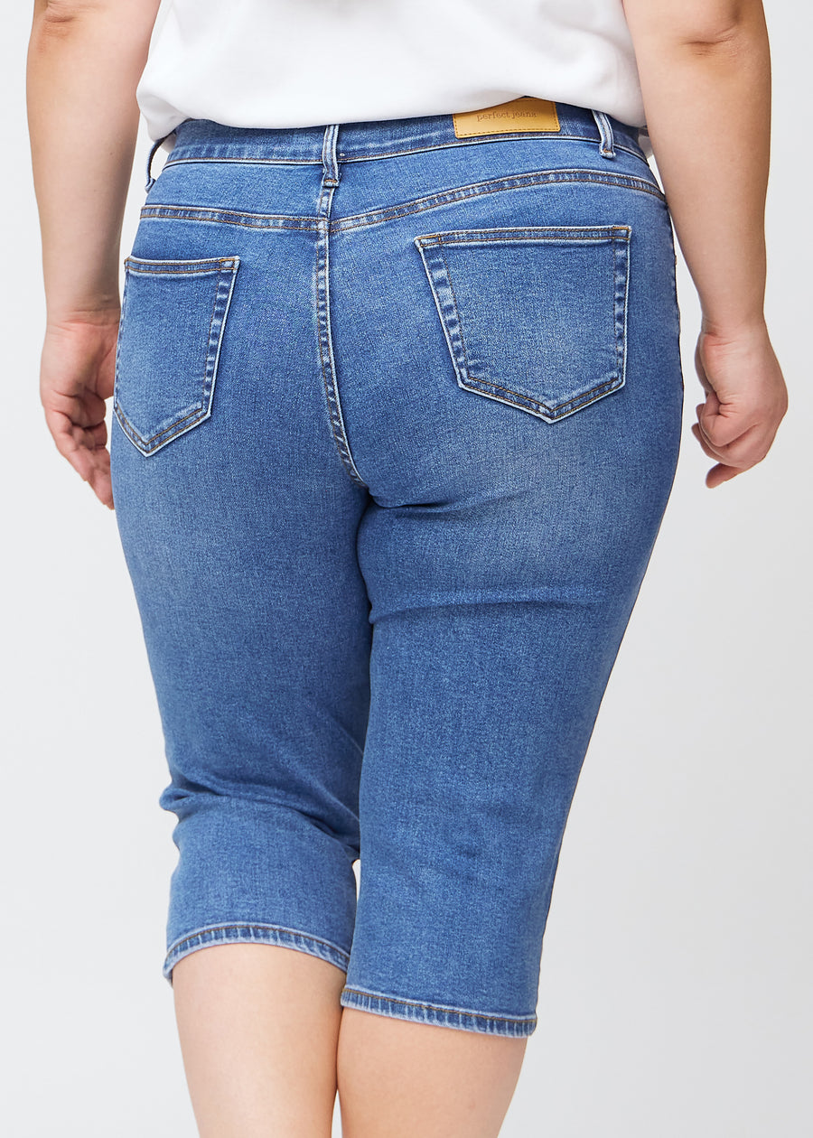 Slim-Capris für Damen aus blauem Denim, Farbe Rivers. Nahaufnahme von hinten an einem Plus-Size-Model, zeigt Taschen und Nähte.