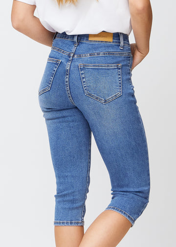 Slim-Capris für Damen aus blauem Denim, Farbe Rivers. Nahaufnahme von hinten an einem Model, zeigt Taschen und Nähte.