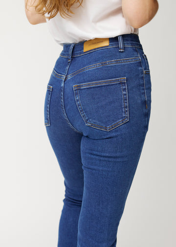 Dunkelblaue Mid-Rise-Bootcut-Jeans in der Farbe Oceans. Nahaufnahme der Rückseite an einem Model, um Details zu zeigen.