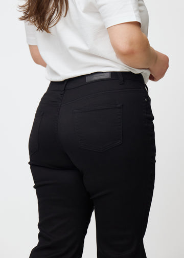 Sorte mid-rise bootcut jeans set bagfra tæt på en plus-size model for at vise detaljer.