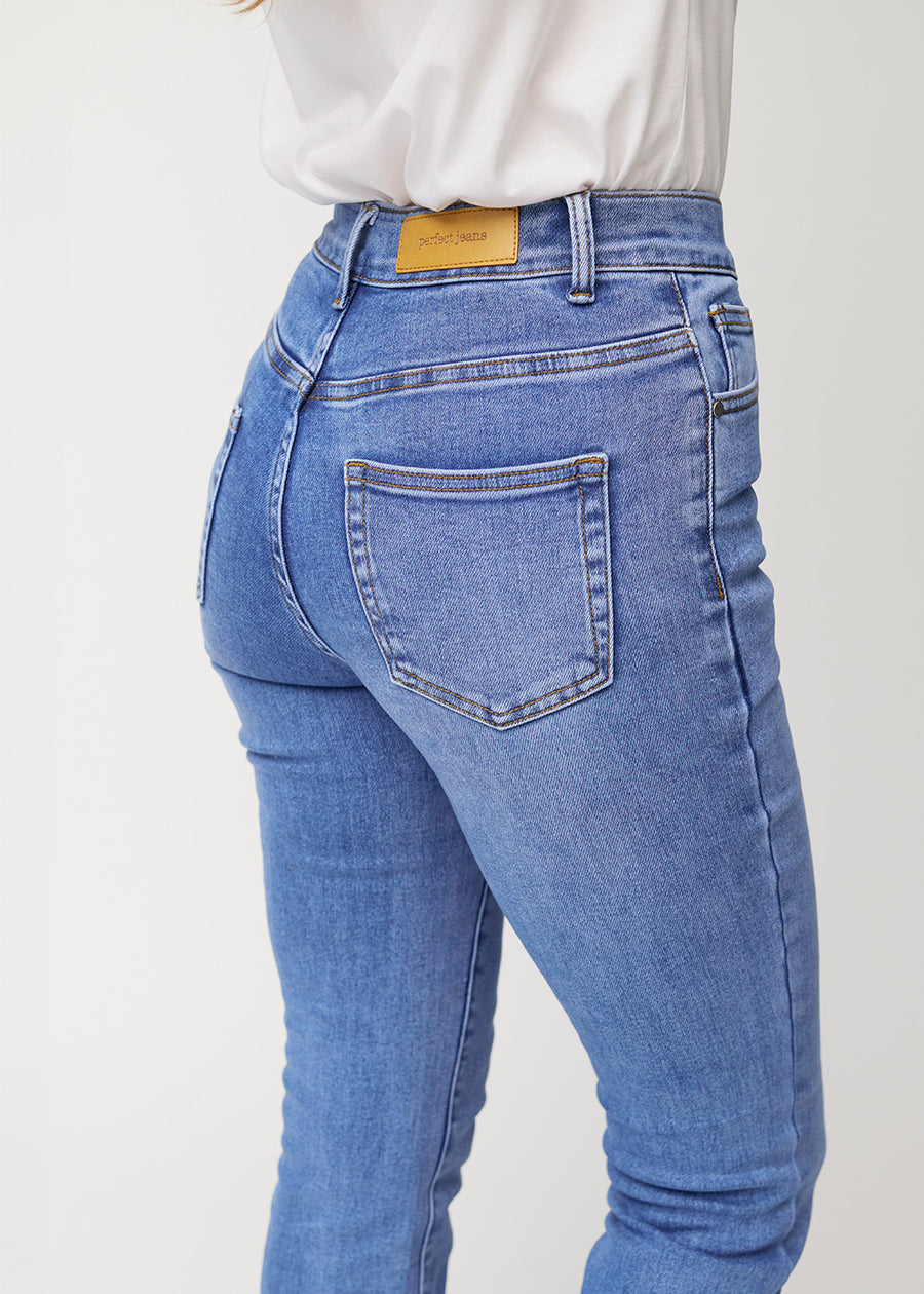 Blaue Mid-Rise-Bootcut-Jeans in der Farbe Rivers. Nahaufnahme der Rückseite an einem Model, um Details zu zeigen.