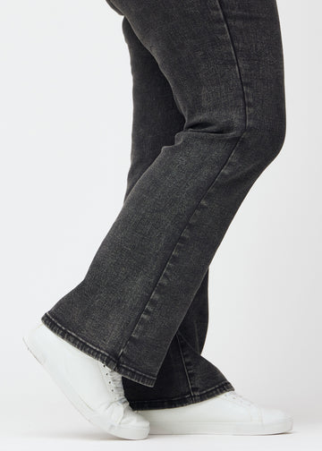 Dunkelgraue Mid-Rise-Bootcut-Jeans in der Farbe Shadows. Nahaufnahme am Knöchel eines Plus-Size-Model, um den leichten Schlag am Beinabschluss zu zeigen.