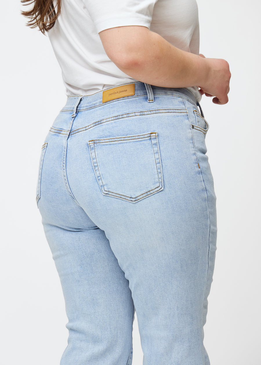 Hellblaue Mid-Rise-Bootcut-Jeans in der Farbe Waves. Nahaufnahme der Rückseite an einem Plus-Size-Model, um Details zu zeigen.