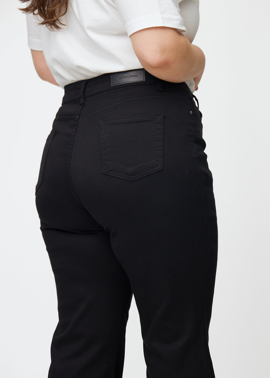 Schwarze hochtaillierte Bootcut jeans von hinten in Nahaufnahme an einem Plus-Size-Model, um Details zu zeigen.