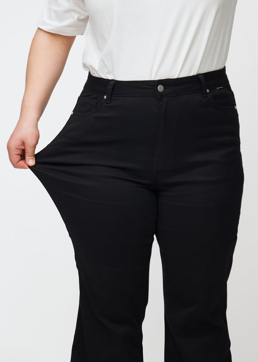 Das Plus-Size-Model zieht die Jeans am Oberschenkel, um den Stretch zu zeigen.