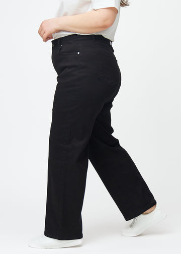 Schwarze hochtaillierte jeans, die an der Taille eng anliegen und eine lockere Passform mit Weite nach unten haben, von der Seite an einem Plus-Size-Model gesehen.