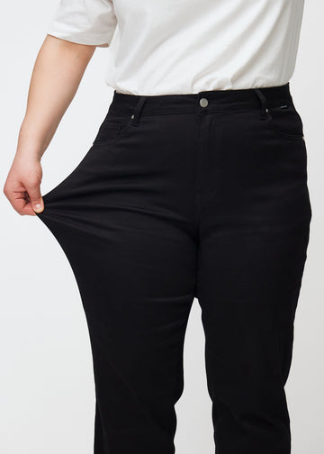 Das Plus-Size-Model zieht die Jeans am Oberschenkel auseinander, um den Stretch zu zeigen.