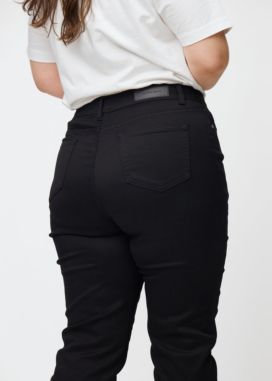 Schwarze hochtaillierte slim jeans von hinten in Nahaufnahme an einem Plus-Size-Model, um Details zu zeigen.