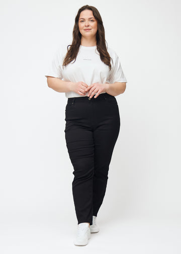 Ganzkörperbild eines Plus-Size-Models in schwarzen hochtaillierten slim jeans.