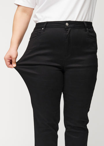 Das Plus-Size-Model zieht die Jeans am Oberschenkel auseinander, um den Stretch zu zeigen.