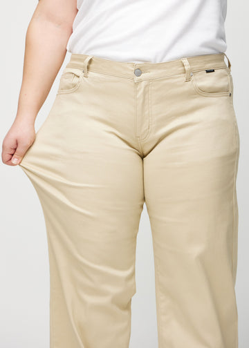 Loose-Jeans für Damen in Beige, Farbe Gazelles. Ein Plus-Size-Model dehnt den Jeansstoff am Oberschenkel, um den Stretch zu zeigen.