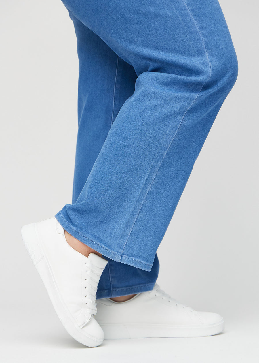 Loose-Jeans für Damen in Blau, Farbe Geraniums. Nahaufnahme an den Knöcheln eines Plus-Size-Models, um die weiten Beinabschlüsse zu zeigen.
