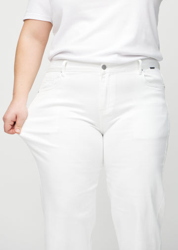 Das Plus-Size-Model zieht die Jeans am Oberschenkel auseinander, um den Stretch zu zeigen.