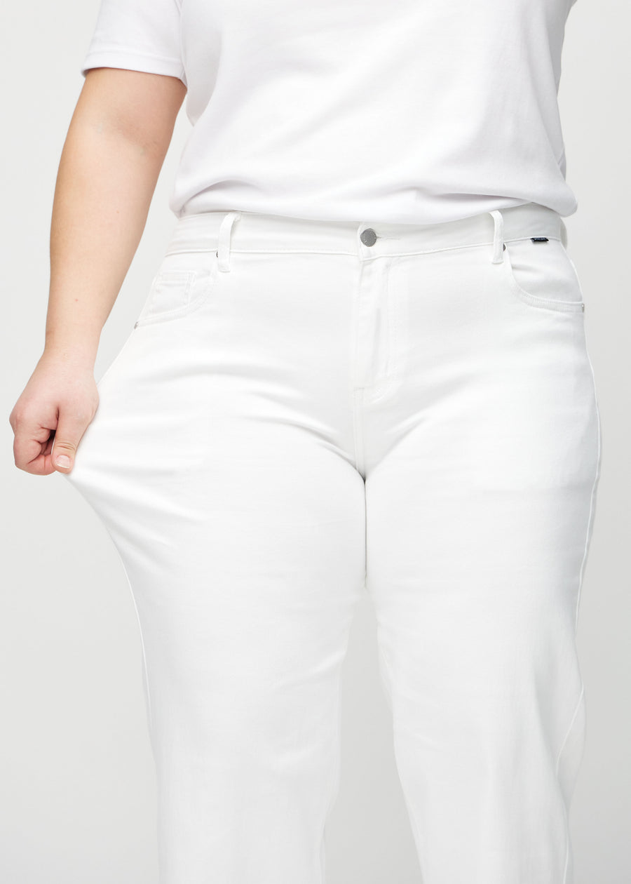 Das Plus-Size-Model zieht die Jeans am Oberschenkel auseinander, um den Stretch zu zeigen.