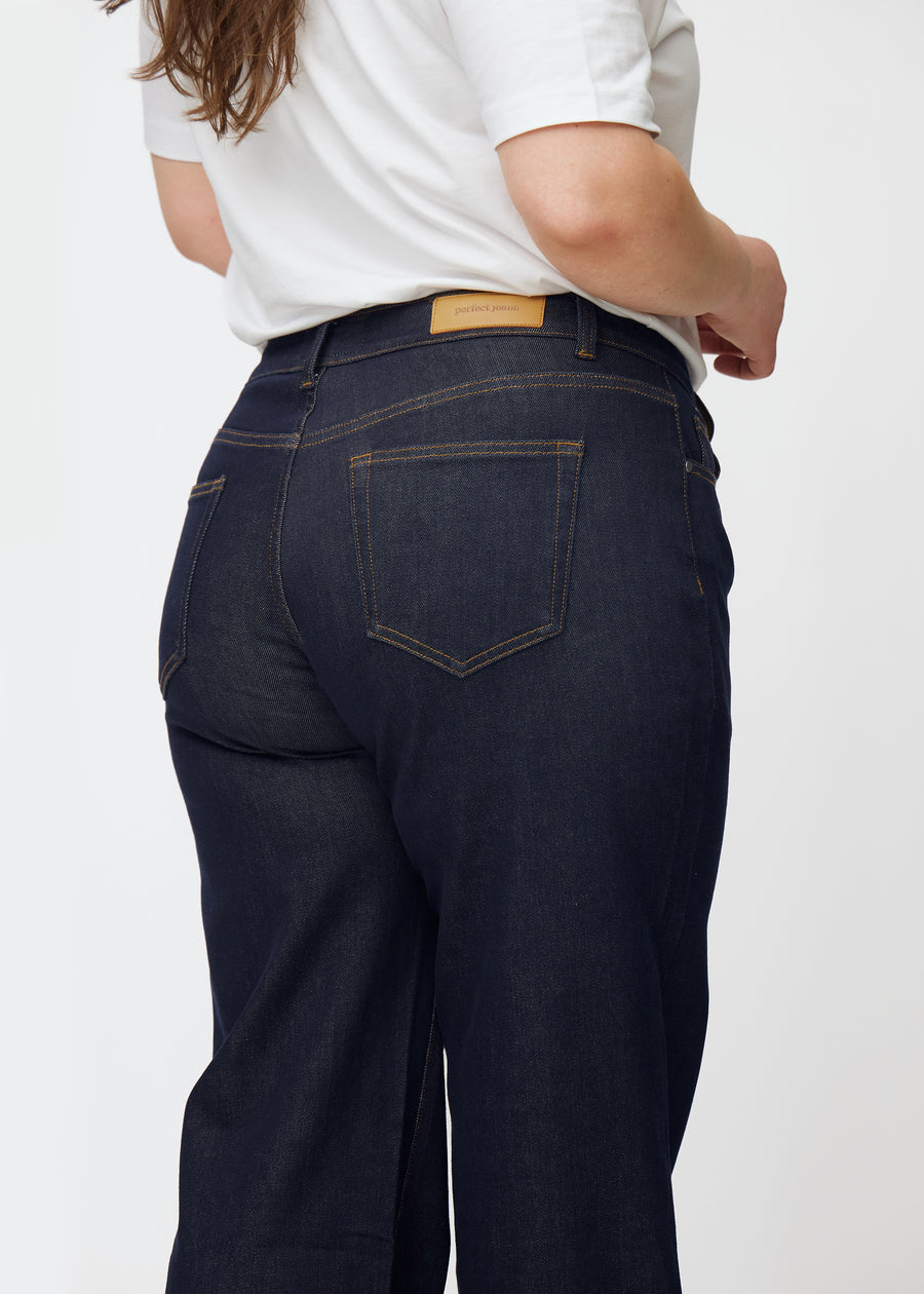 Tief dunkelblaue Denim jeans für Damen in der Farbe Midnights, von hinten als Nahaufnahme an einem Plus-Size-Model gezeigt.