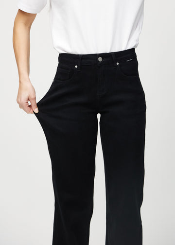 Loose-Jeans für Damen in Schwarz, Farbe Ravens. Ein Model dehnt den Jeansstoff am Oberschenkel, um den Stretch zu zeigen.
